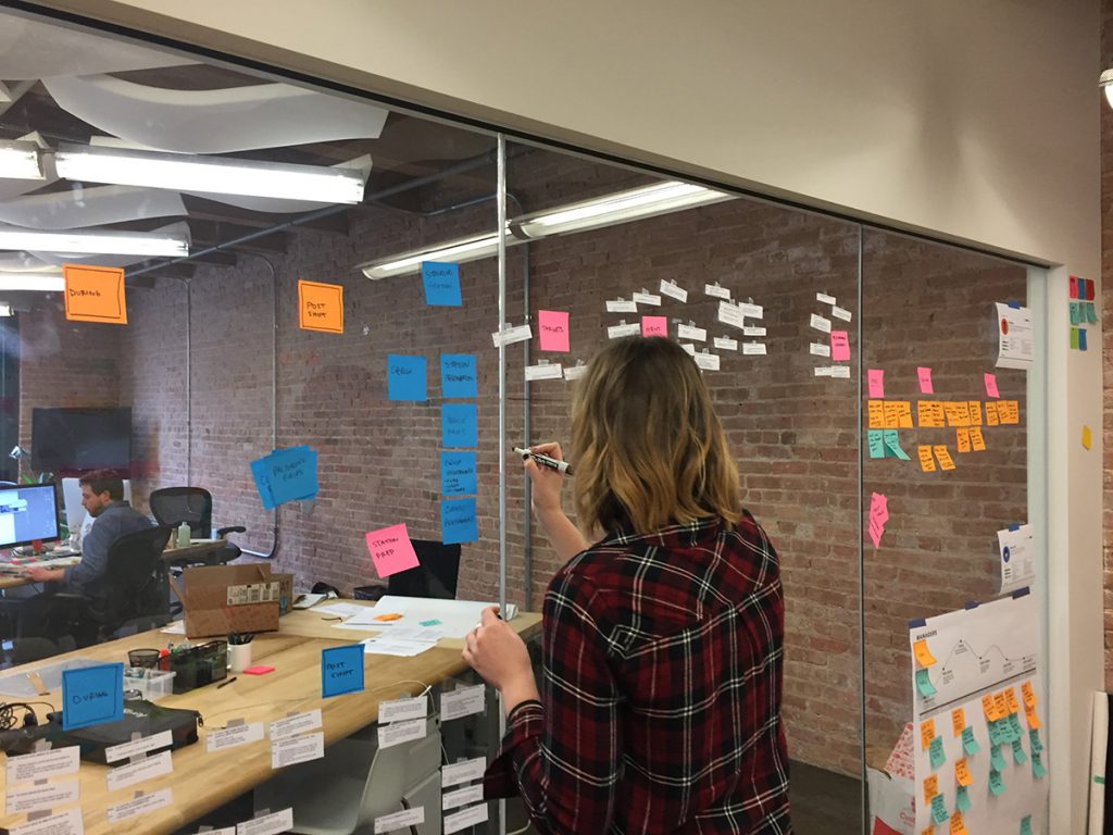 A Grand Studio designer works through ideas on post-its stuck to the wall