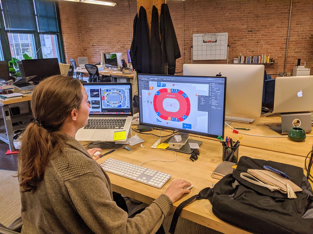 A Grand Studio designer layout out a map of a basketball stadium on a computer